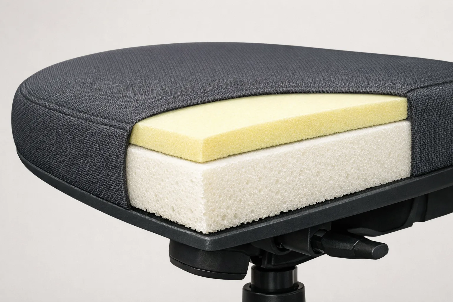 Coupe d’une assise de fauteuil montrant une couche supérieure de mousse au-dessus d’un rembourrage de soutien.