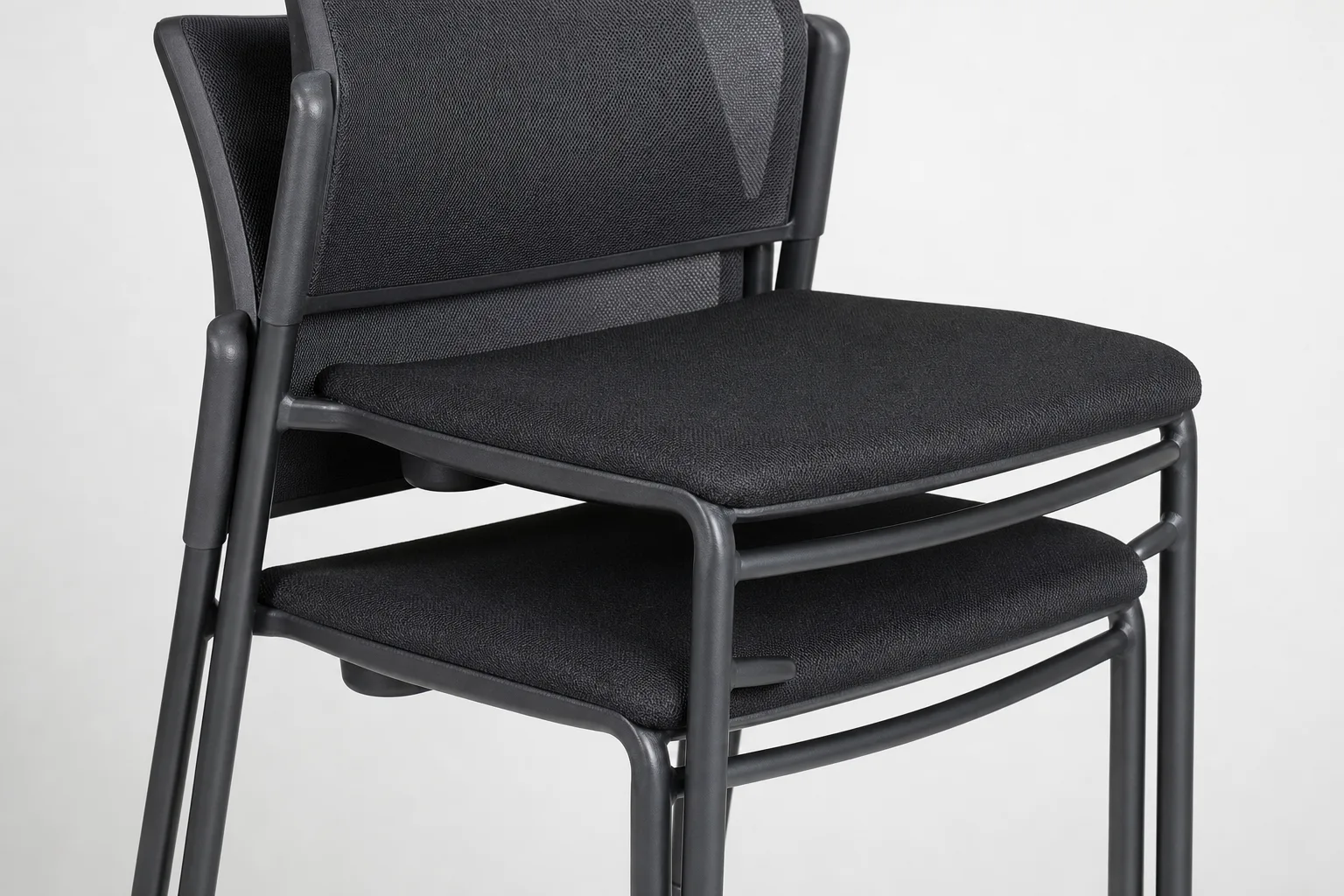 Deux chaises empilables partiellement emboîtées, avec les pieds et les traverses des châssis visibles.