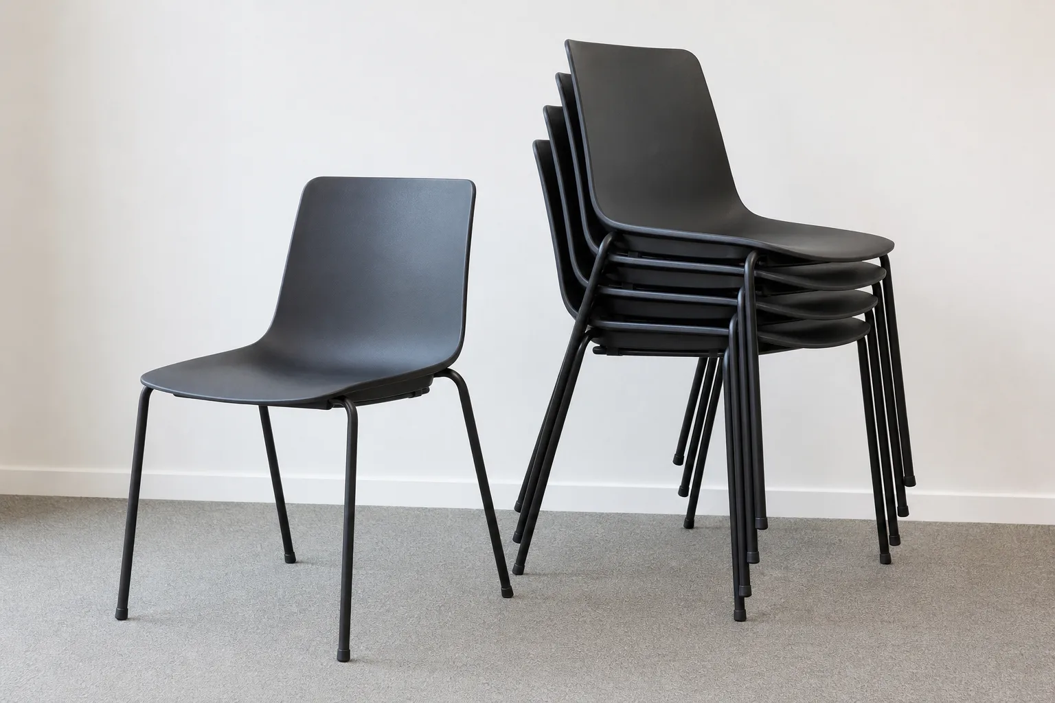 Pile de chaises de bureau à châssis tubulaire, avec une chaise identique posée seule à côté.