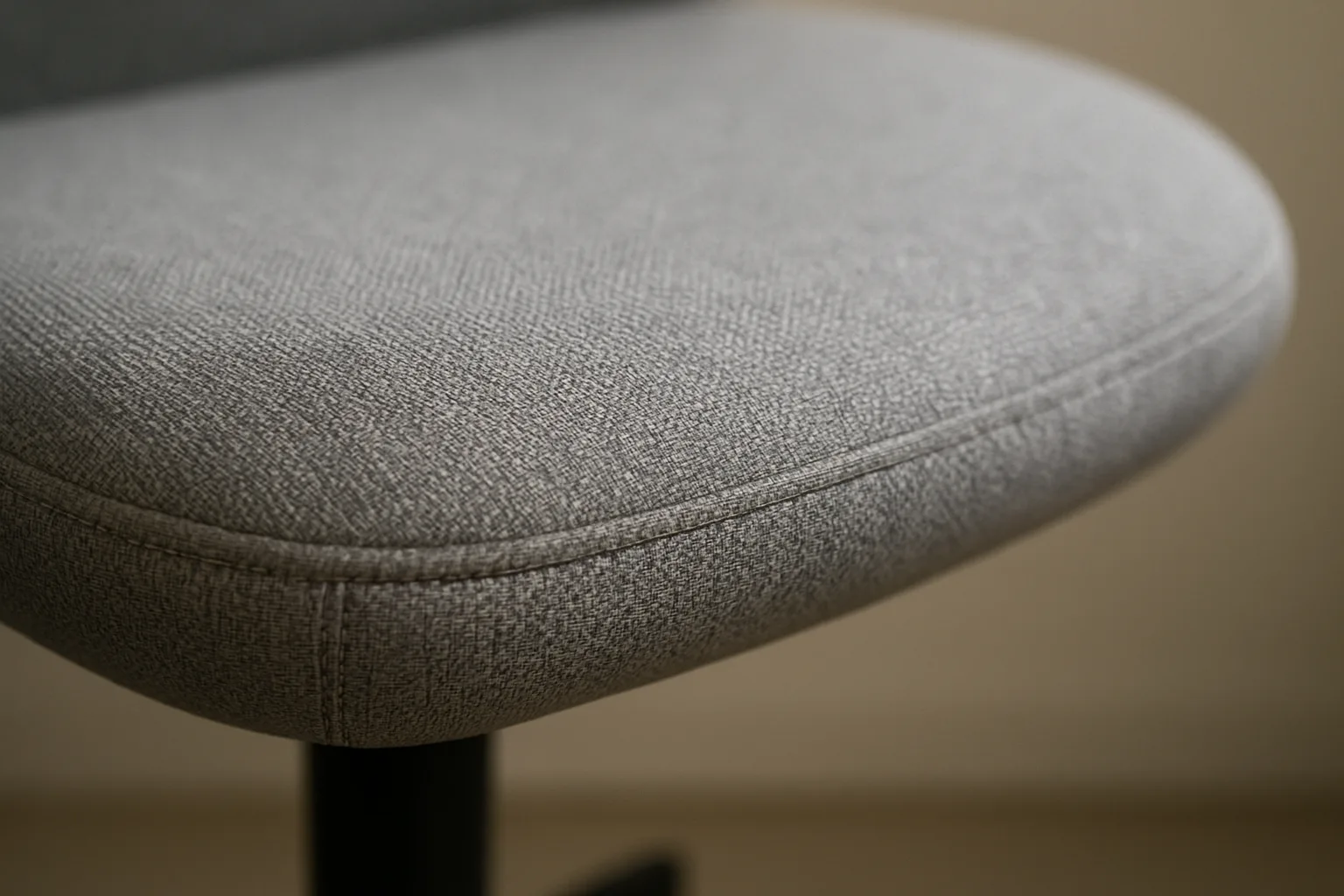 Gros plan sur la couture en tissu au bord d’une assise rembourrée de fauteuil de bureau.