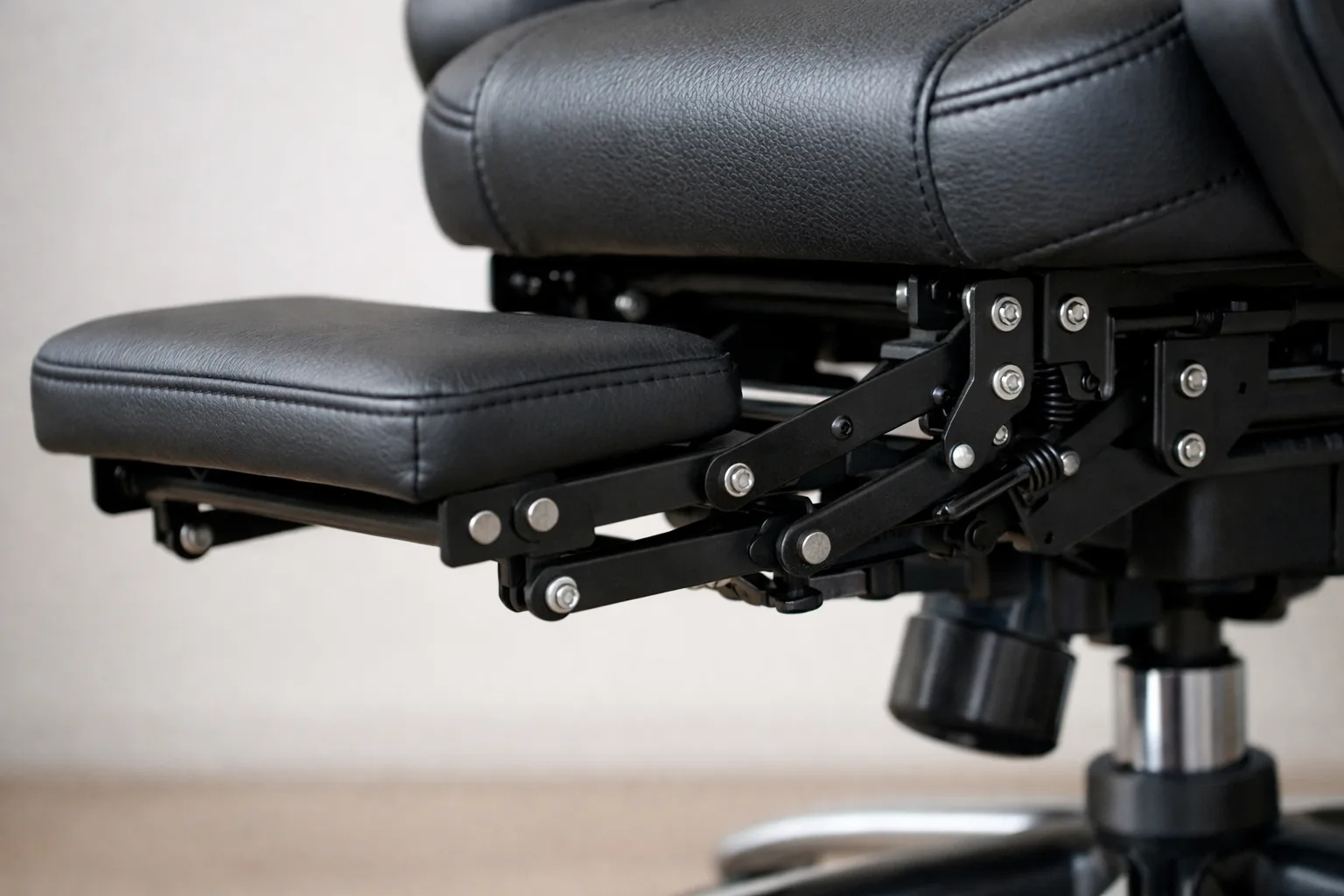 Articulations et fixations visibles sous le repose-jambes déployé d’un fauteuil de bureau.