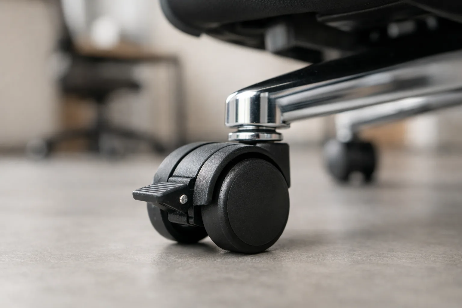 Gros plan sur une roulette freinée montée sous le piètement d’un fauteuil de bureau.